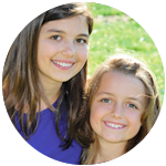 Two young girls side by side smiling in outdoor setting