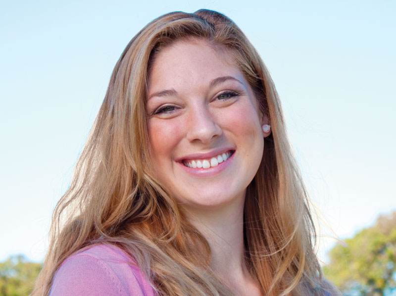 Young woman smiling and standing outside on a sunny day